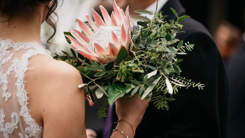 Shallow focus shot of a bride holding a bouquet with a king protea flower