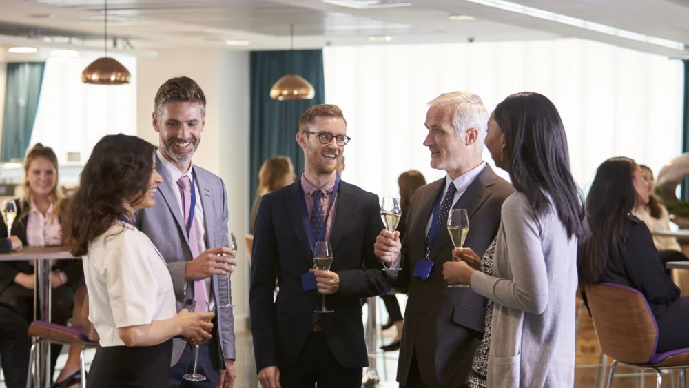 A group of people standing around each other holding wine glasses