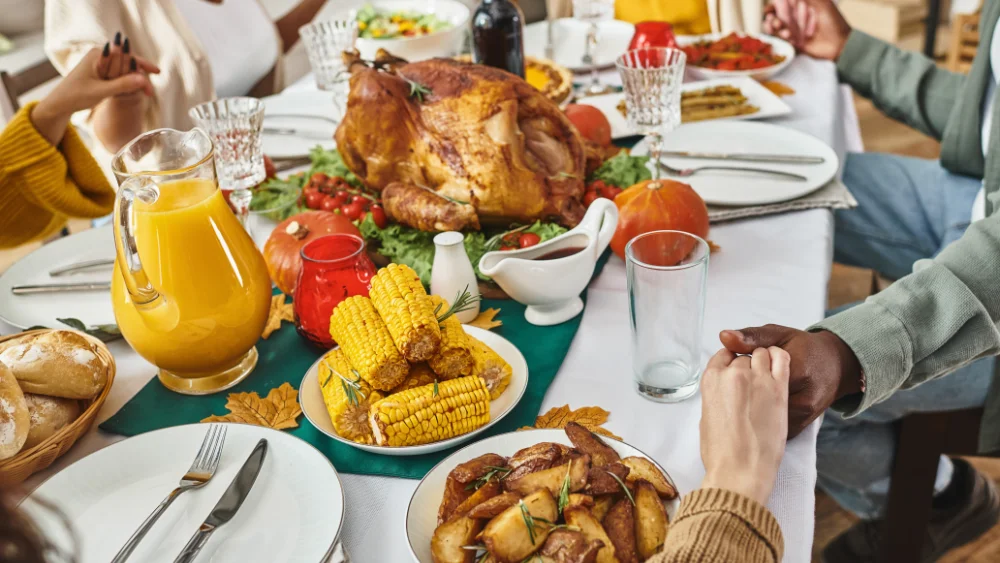 family holding hands around a table during thanksgiving dinner